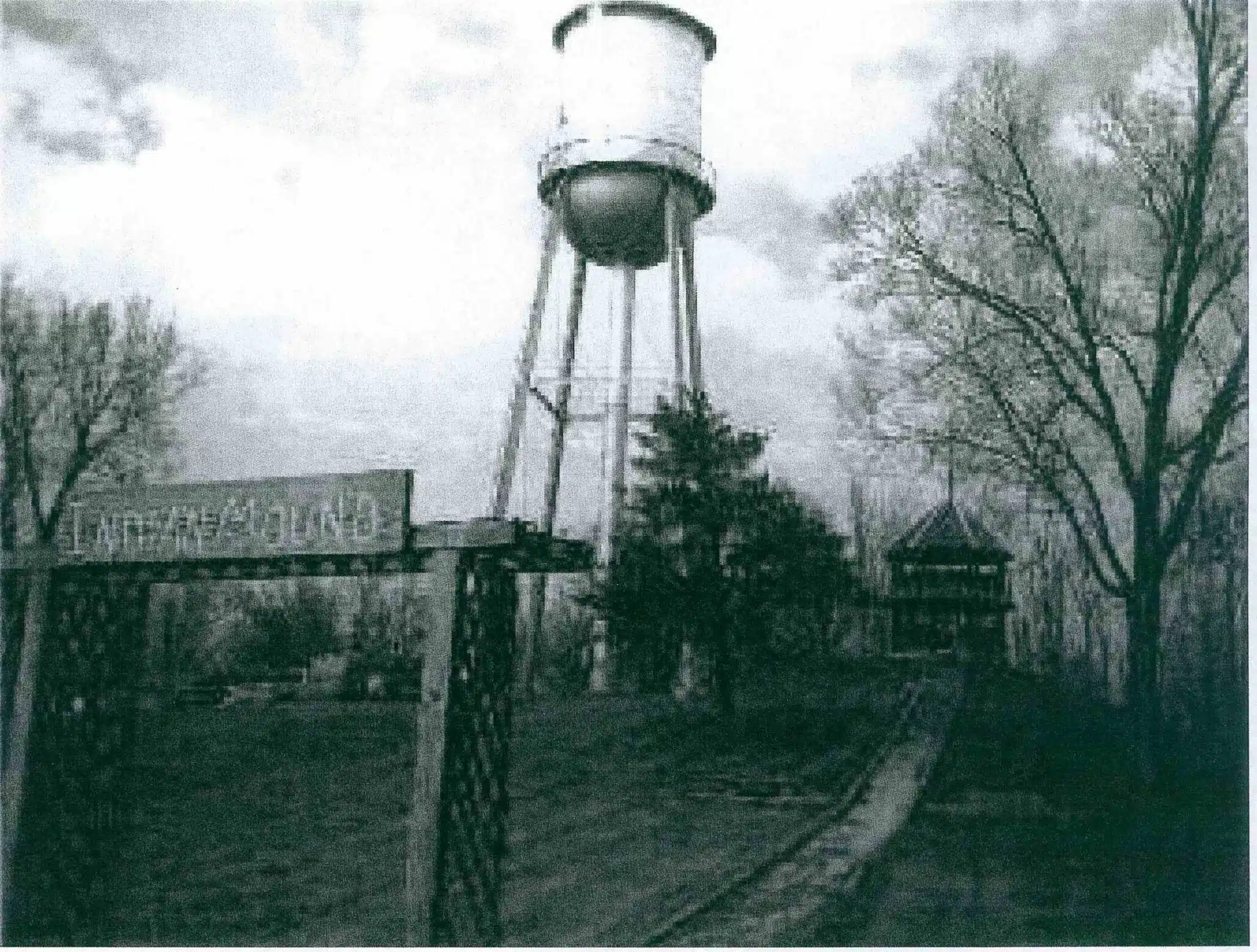 Photo with caption: Not the clearest image, but one we are lucky to have in the Laurel Library’s collection. From left to right one can see the park entrance sign that said “Indian Mound,” the old water tower, and the bandstand on top of the mound.
